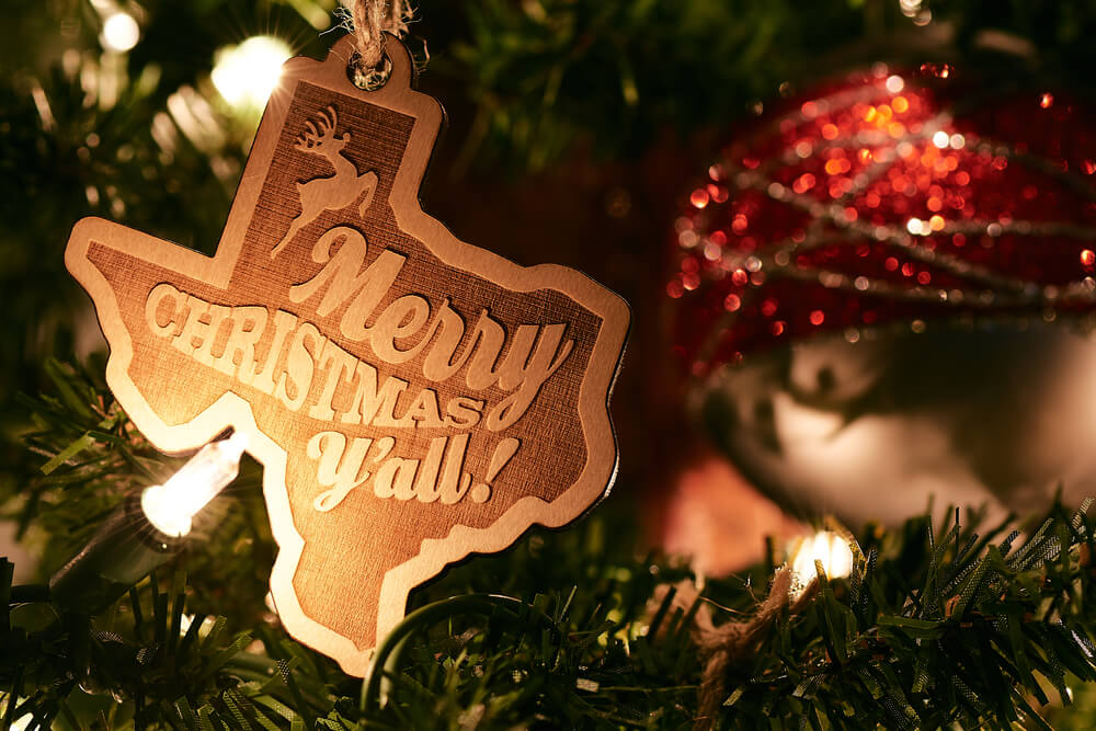 A Texas-shaped ornament that reads "Merry Christmas Y'all!" hangs on a Christmas Tree, marking the Fredericksburg Holidays.
