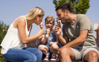 A mom and dad eat ice cream with their young child, one of the many summer activities in Fredericksburg, TX.