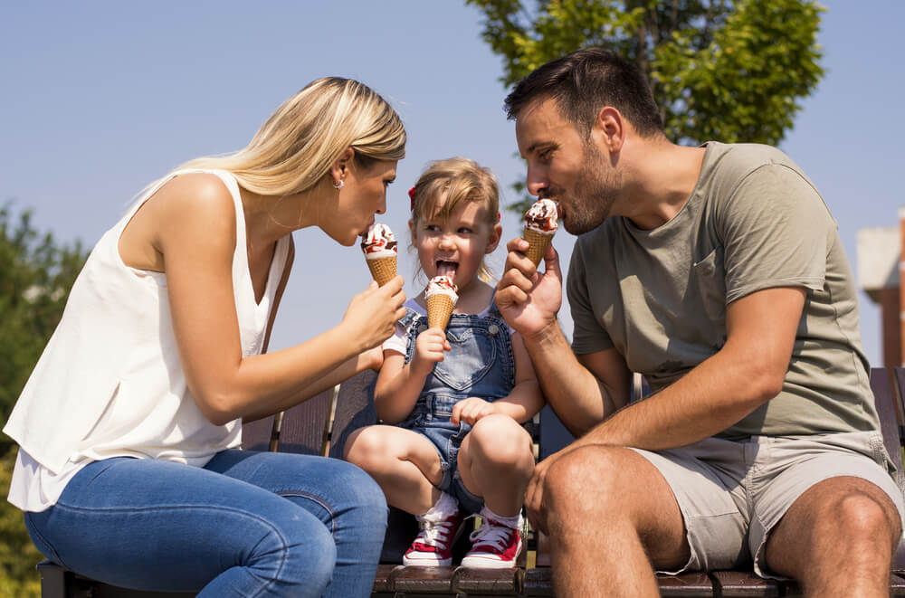 A mom and dad eat ice cream with their young child, one of the many summer activities in Fredericksburg, TX.