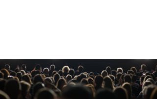 An audience sits in front of a large, white screen at the Hill Country Film Festival.